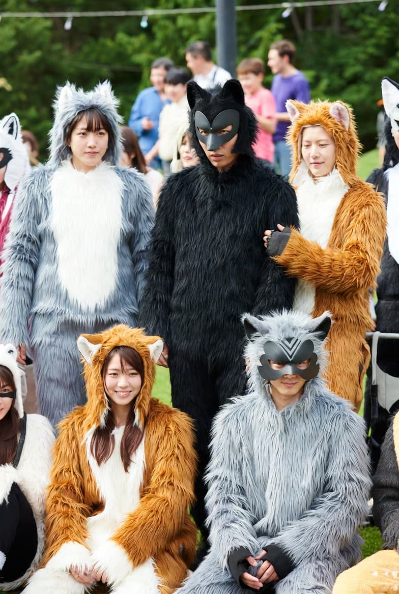 People wearing grey, black, and brown furry animal costumes and masks posing outdoors.