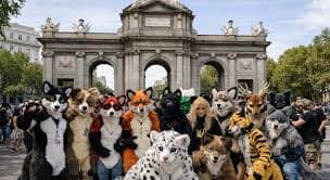Large group of furries in animal costumes posing in front of a grand stone archway.
