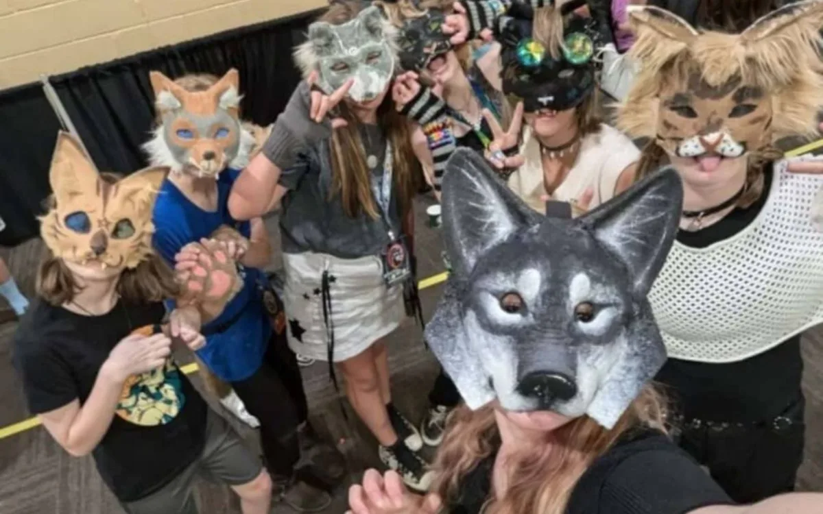 Group of people wearing animal masks, including wolves and cats, posing for a group selfie.